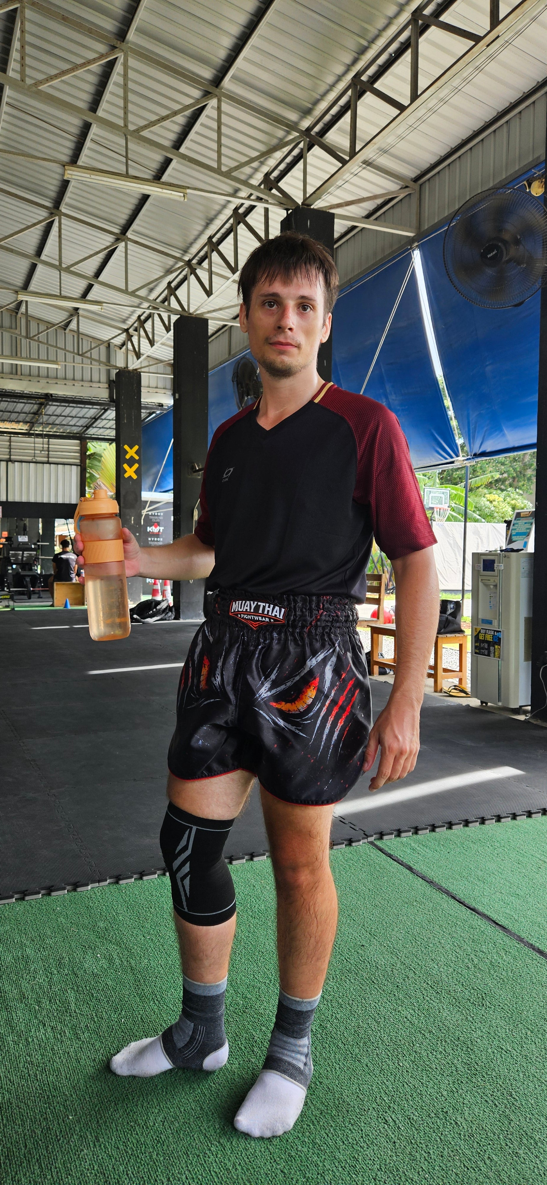 Shadow Predator Muay Thai shorts – fighter in powerful side stance with dark predator design – order premium fight shorts Thailand
