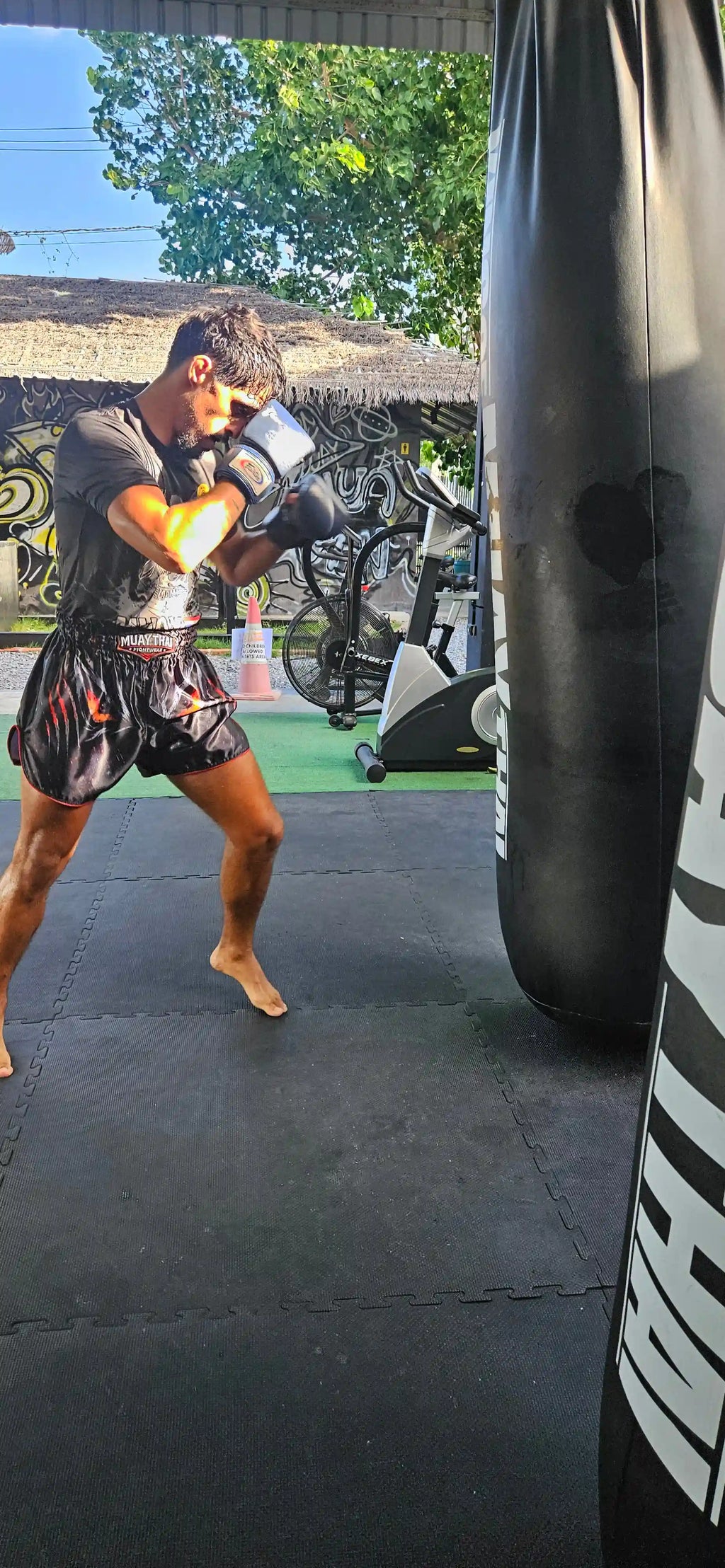 Shadow Predator Muay Thai shorts – fighter in intense gym training with dark predator design – shop elite fight wear Thailand
